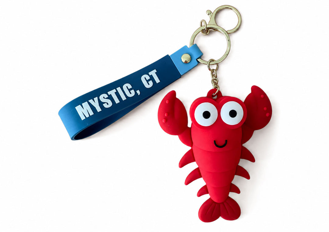 The Mystic Seaport Museum Lobster Squeeze Keychain features a smiling red lobster, a blue MYSTIC, CT strap, and a gold key ring—an ideal nautical souvenir for fans of Mystic Seaport Museum.